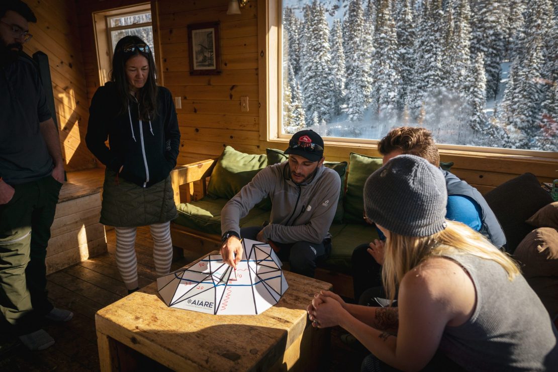 San Juan Expeditions guide and instructor teaching students slope angle and aspect in a backcountry hut