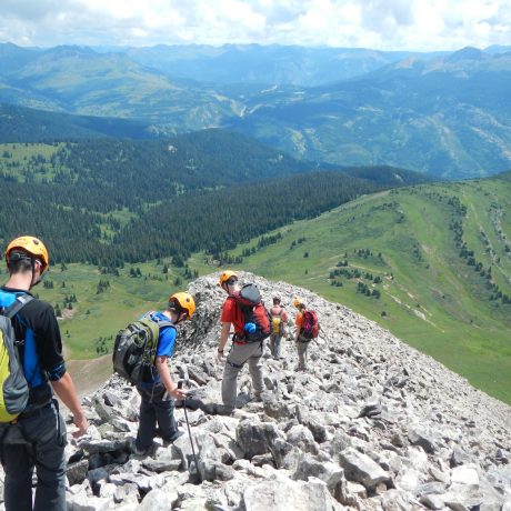  A group of climbers descending the Northeast Ridge of Engineer with rolling green alpine meadows in the background.