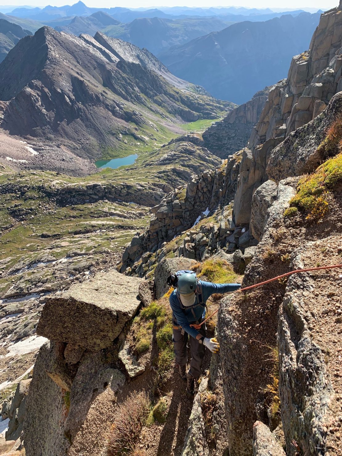 San Juan Expeditions client climbing up Jagged on a rope with alpine lakes in the background